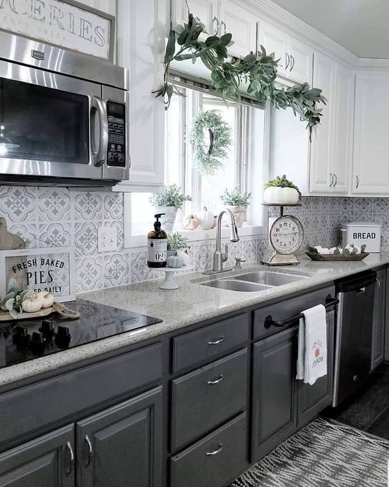 Beyaz ust dolaplar grafit gri alt dolaplar mozaik fayans arka zemini ve tas tezgahlarla sik bir mutfak