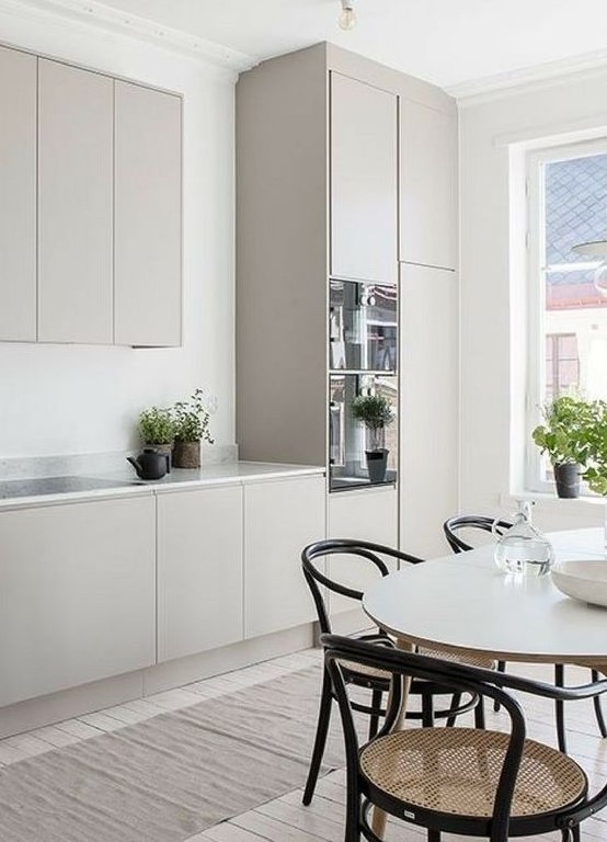 Davetkar bir Iskandinav mutfak duz gri dolaplar beyaz mermer tezgah oval bir masa ve sik retro hasir sandalyeler ile tasarlanmistir
