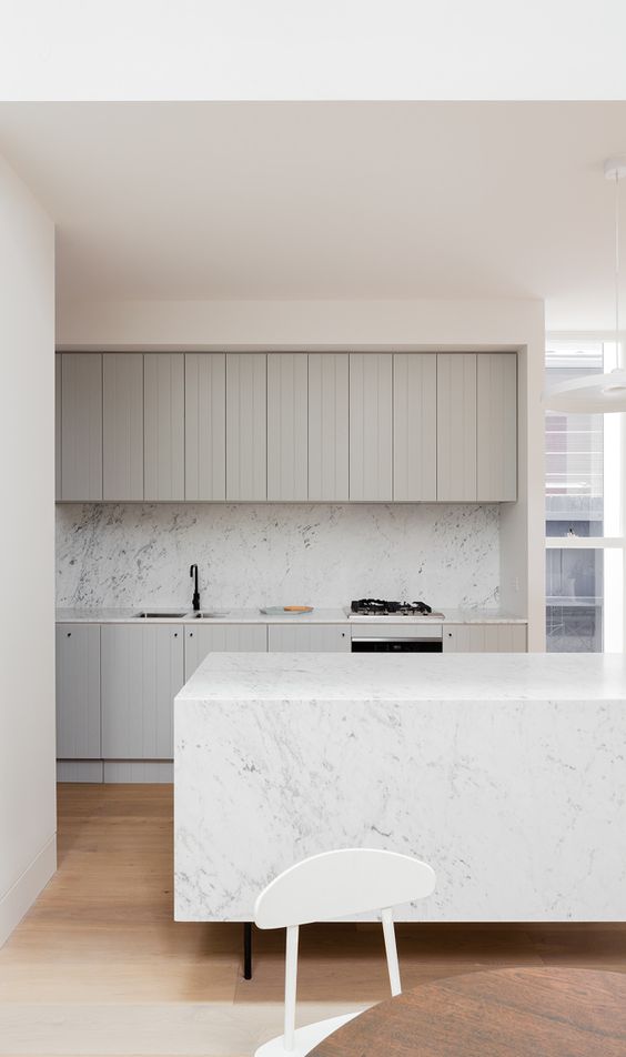 Guvercin grisi ters dolaplar beyaz mermer backsplash ve uyumlu bir mutfak adasi ile guzel bir minimalist mutfak